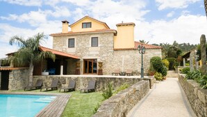 Una casa de piedra con piscina, mobiliario de exterior y jardín.