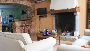 A living room with a fireplace, a television mounted above it, and a kitchen area in the background. - House / Villa - Trélou sur Marne (Trélou-Sur-Marne)