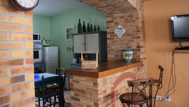 A kitchen with a brick arch, a microwave, a refrigerator, a dining table with chairs, and a sign indicating a wine cellar. - House / Villa - Trélou sur Marne (Trélou-Sur-Marne)