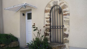 A building with a white door, a stone archway with a metal gate, and a small garden with purple flowers. - House / Villa - Trélou sur Marne (Trélou-Sur-Marne)