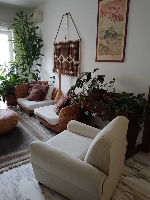 A living room with a sofa, armchair, hanging plant, and a framed picture on the wall. - Your home in the heart of bari near beach old town and station (Bari)