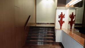 A hallway with a staircase leading to a landing, a wooden door, and a counter with a reflective surface. - Your home in the heart of bari near beach old town and station (Bari)