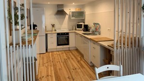 A compact kitchen with white cabinetry, a built-in oven, a microwave, and a sink.