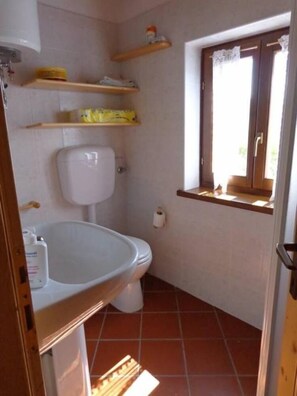 A small bathroom with a toilet, a sink, and shelves above the toilet. - Chalet surrounded by greenery near MTB routes (Castello Tesino)