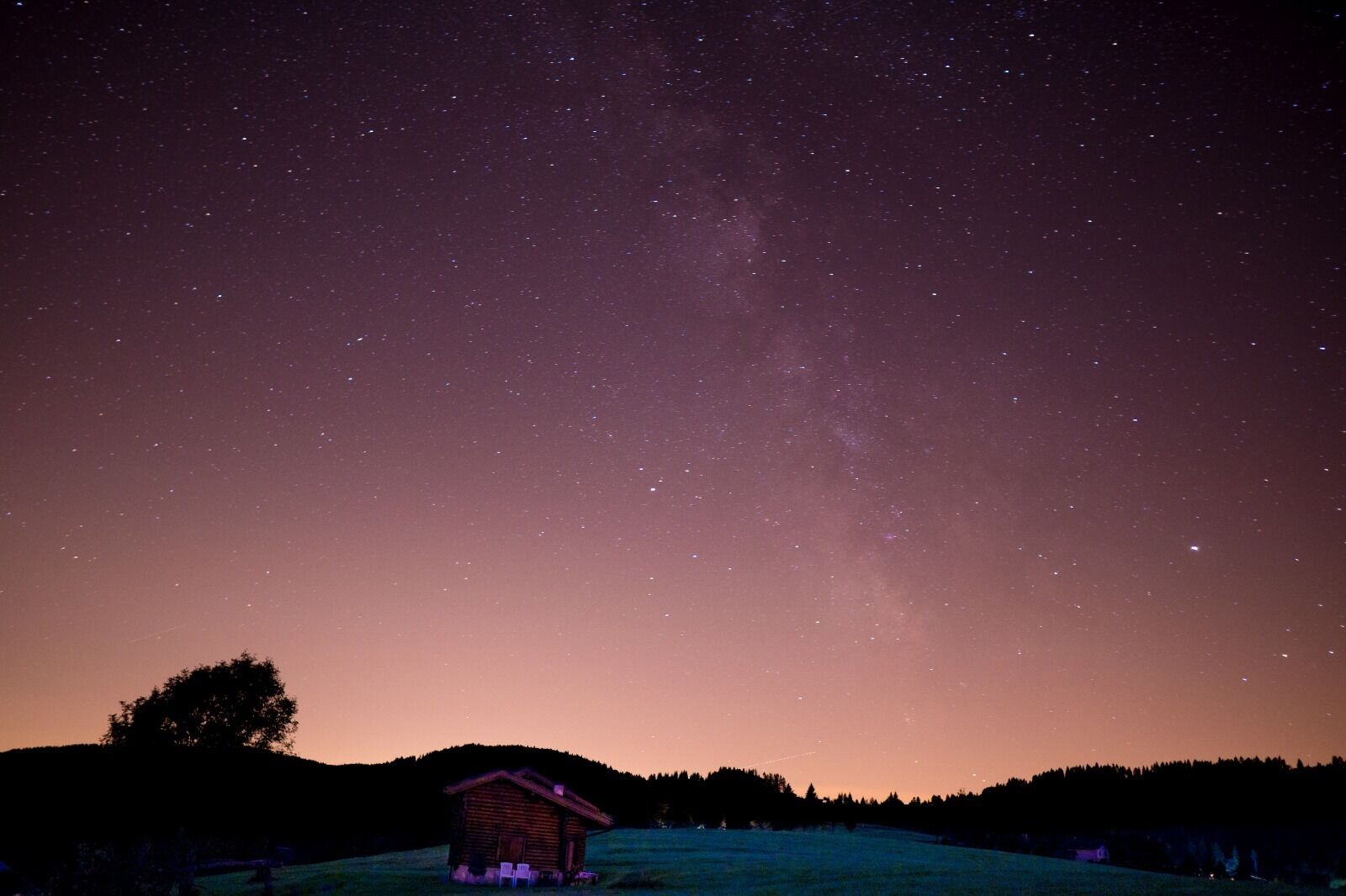 A small cabin with a starry night sky above.