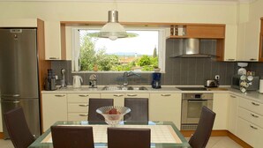 A modern kitchen with a dining area, stainless steel appliances, and a view of greenery outside. - Fantastic villa with a swimming pool ideal for a relaxing vacation and more... (Messini, Messinia)