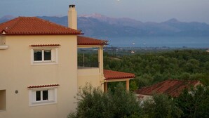 A two-story building with a red-tiled roof, a balcony, and a view of mountains in the background. - Fantastic villa with a swimming pool ideal for a relaxing vacation and more... (Messini, Messinia)