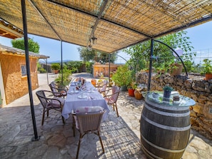 An outdoor patio with a table set for dining, surrounded by wicker chairs, under a bamboo canopy. - Villa Son Fullos ·Villa with private pool in Santa Margalida (Santa Margalida)