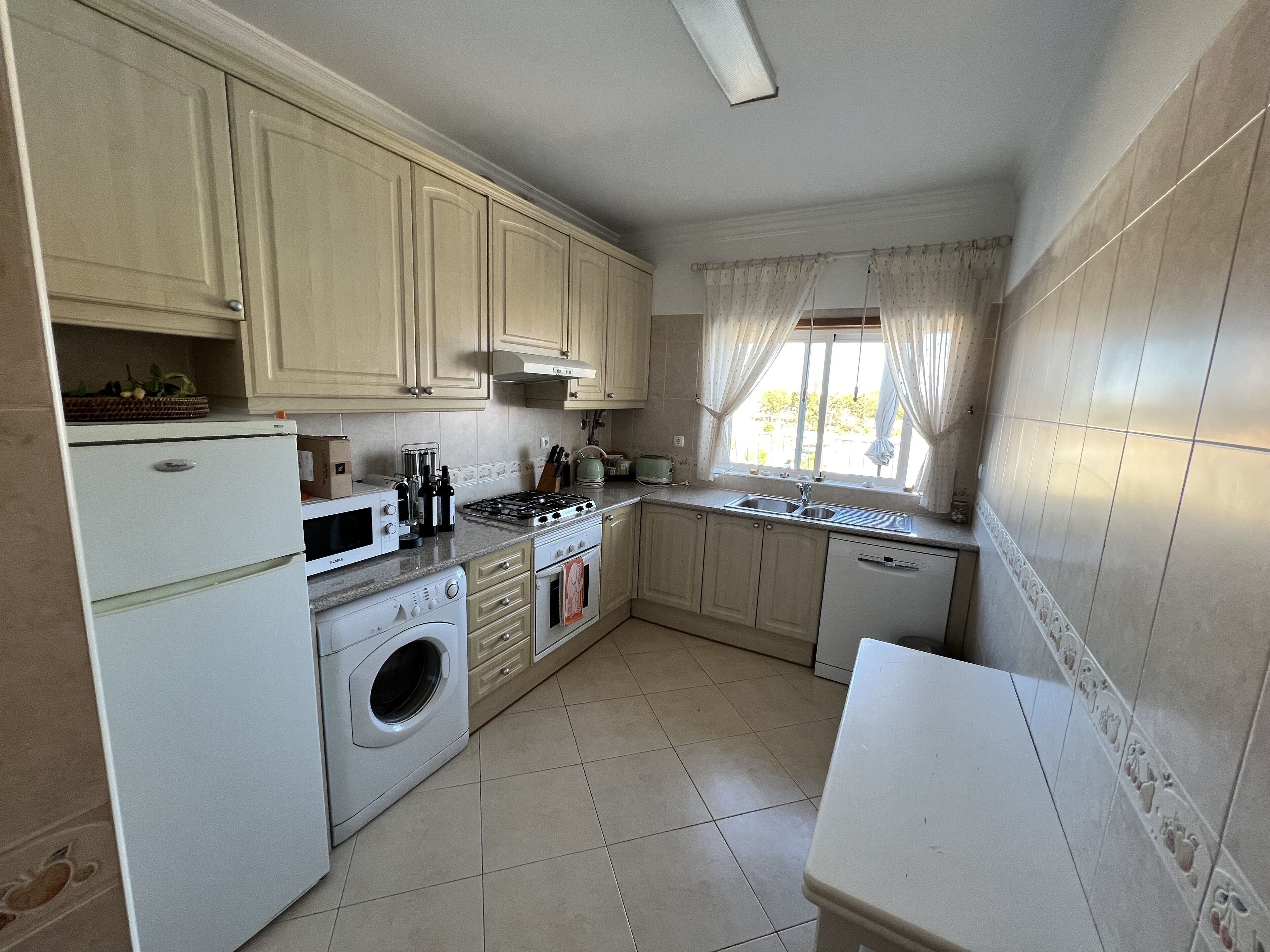 A compact kitchen with a washing machine, microwave, stove, sink, and cabinets.