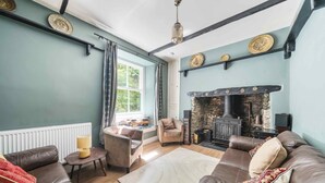 A cozy living room with leather sofas, a fireplace, and a bookshelf. - Large Period House set in Ancient Woodland in Exmoor National Park near Lynmouth (Lynton)