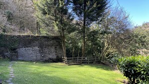 A stone wall, a wooden fence, and a grassy area with a stone path. - Large Period House set in Ancient Woodland in Exmoor National Park near Lynmouth (Lynton)