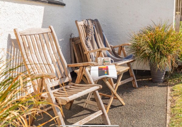 Two wooden chairs and a table with a magazine and two mugs.