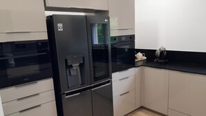 Una cocina moderna con un refrigerador negro, un dispensador de agua y una cafetera sobre la encimera.