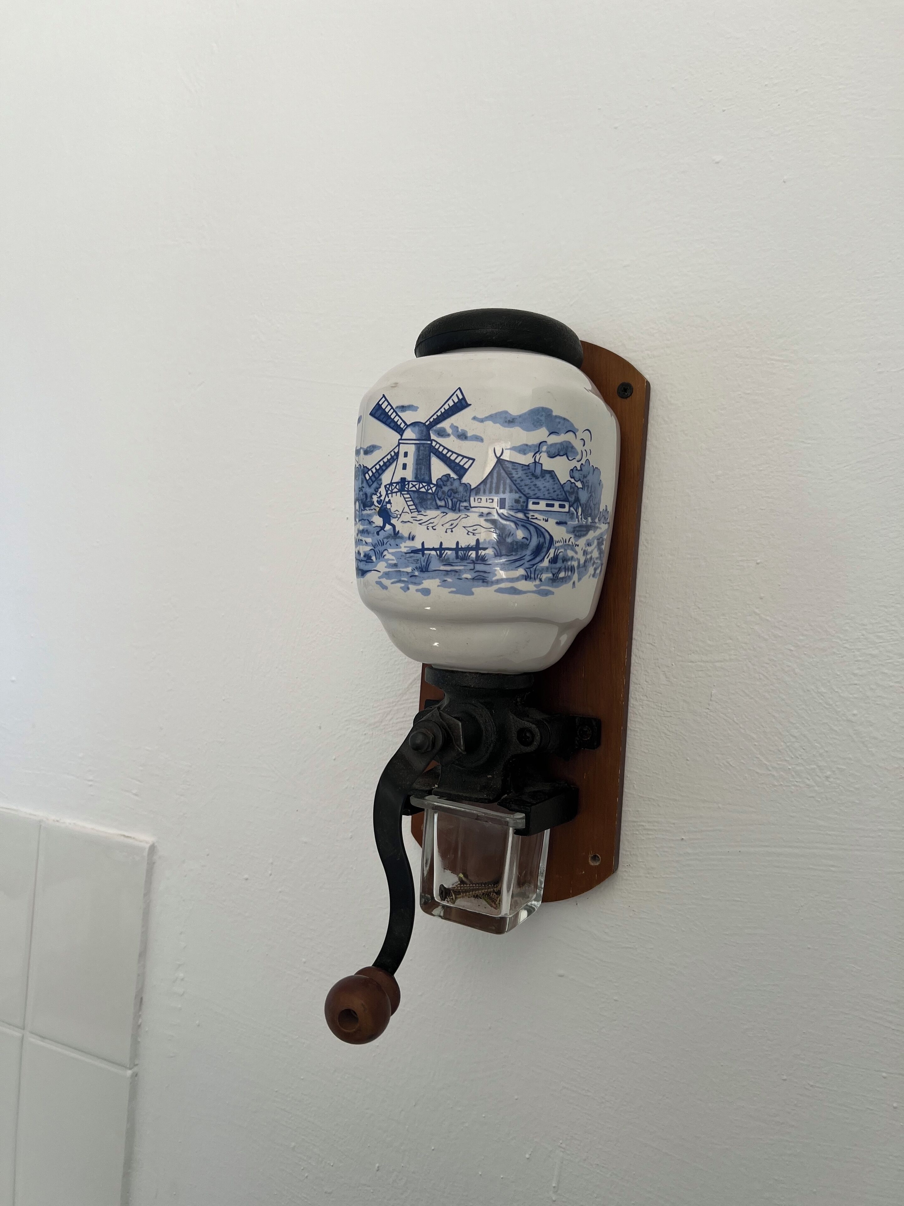 A wall-mounted ceramic object with a blue and white design, featuring a windmill and a house.