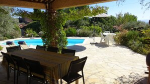 Un patio exterior con piscina, mesa de comedor, sillas y una lámpara de mesa.
