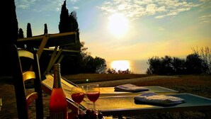 A sunset view from a terrace with a bottle of Beni olive oil, two glasses of red wine, and a plate of grapes. - 'Stunning Views': beachfront villa with pool (Garda)