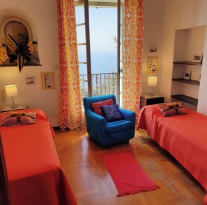 A room with two beds, a blue armchair, and a red rug. - 'Stunning Views': beachfront villa with pool (Garda)