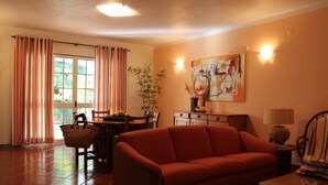 Ein Wohnzimmer mit einer Couch, einem Esstisch mit Stühlen, einer Lampe und einem Gemälde an der Wand.