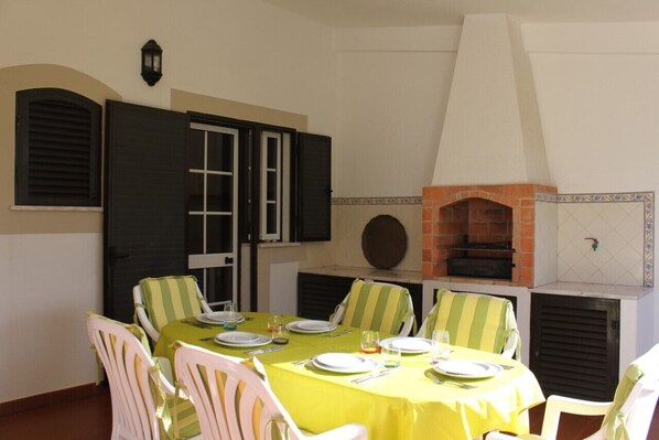 Un comedor con una mesa preparada para cuatro personas, rodeada de sillas con cojines a rayas.