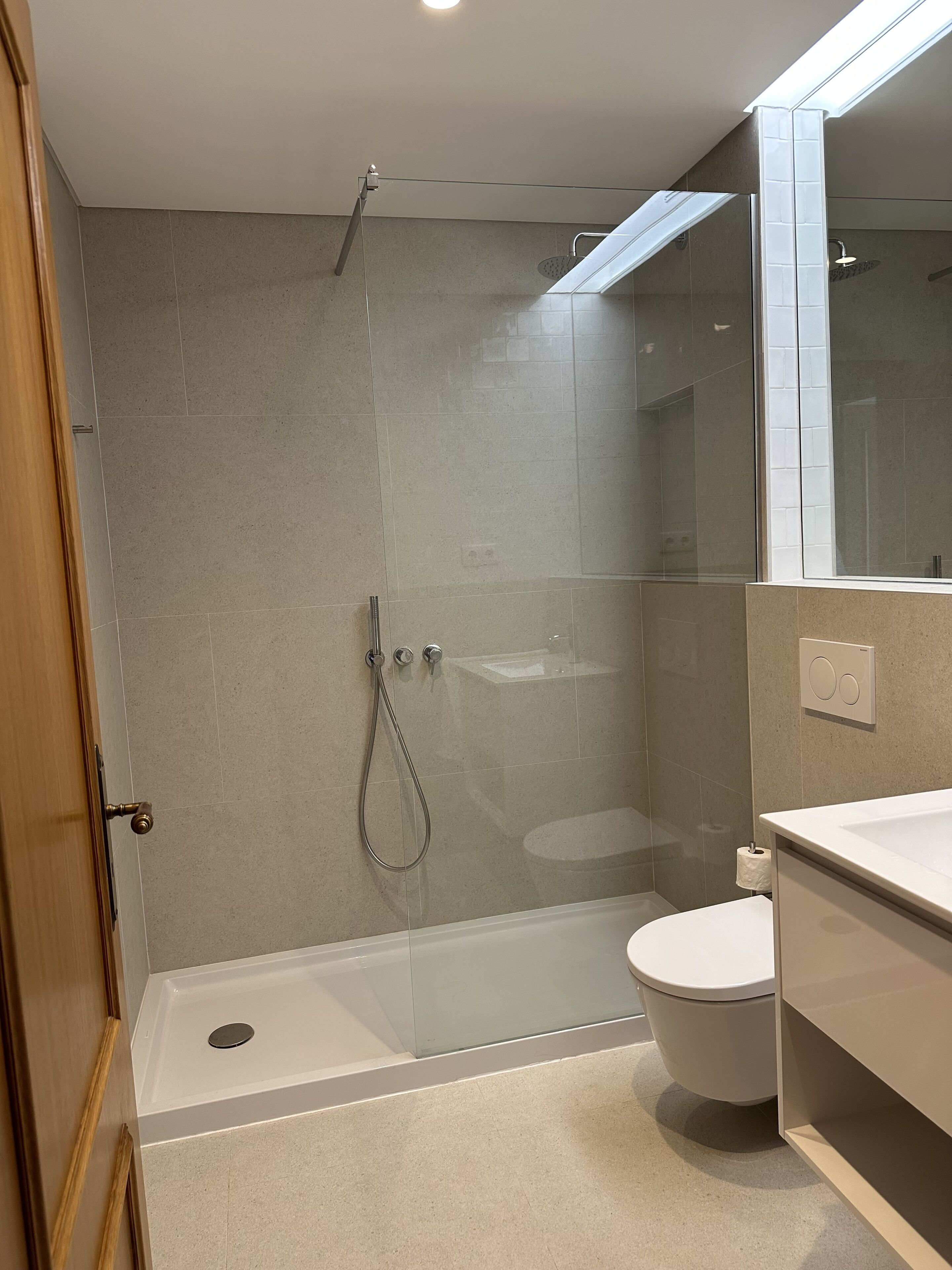 Un baño moderno con ducha de vidrio, inodoro y lavamanos.