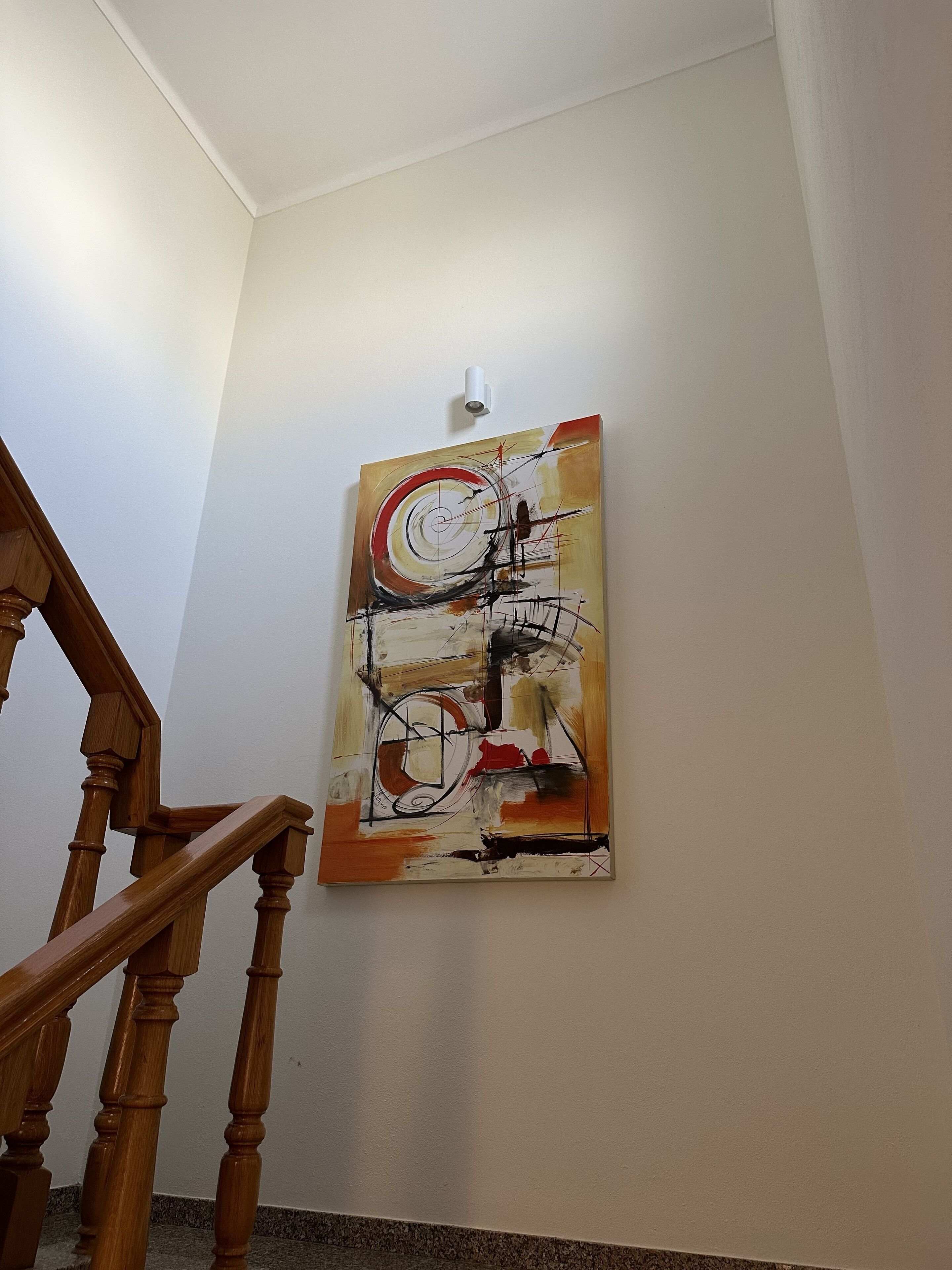 Una escalera con barandas de madera y un cuadro abstracto colgado en la pared.
