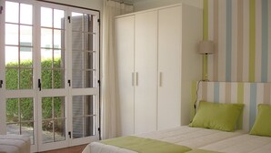 Ein Schlafzimmer mit Bett, Kleiderschrank und einem Fenster mit Vorhängen.