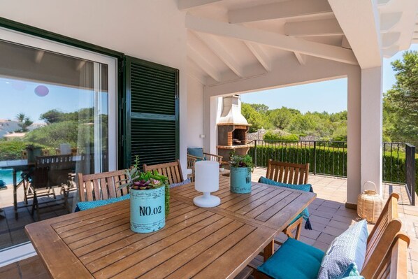 An outdoor patio with a wooden table, chairs, and potted plants.