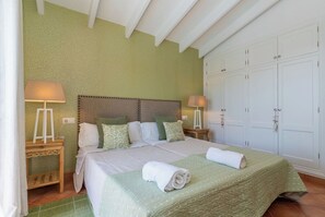 A bedroom with a bed, two bedside tables, a nightstand, a wardrobe, and a green carpet.