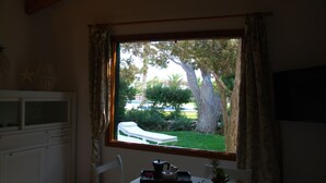 Une pièce donnant sur un jardin, une table à manger avec un plateau rempli de divers objets, et un buffet blanc.