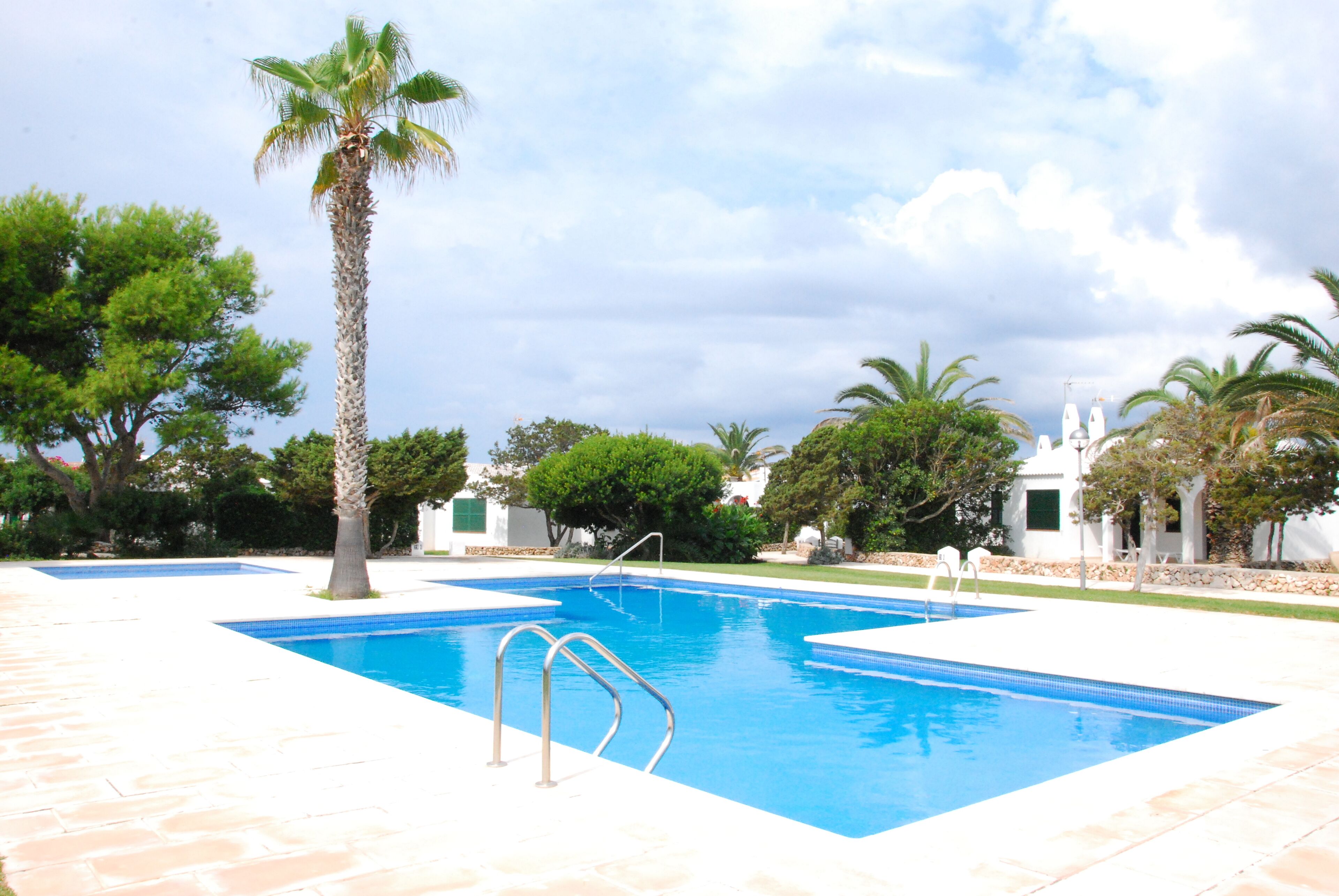 A rectangular swimming pool with a clear blue water, surrounded by a stone deck.