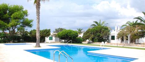 A rectangular swimming pool with a clear blue water, surrounded by a stone deck.