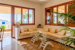 Ein Wohnzimmer mit einer Couch, einem Glastisch und großen Fenstern.