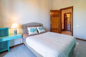 A bedroom with a bed, a bedside table with a lamp, a wardrobe, and a bathroom visible through an open door.