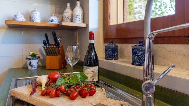 Eine Küchenarbeitsplatte mit Schneidebrett, Tomaten, einer Weinflasche und Küchenutensilien.