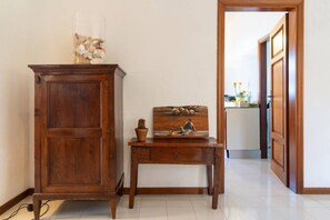 Ein Holzschrank und ein kleiner Tisch mit einem Gemälde und einer Topfpflanze.