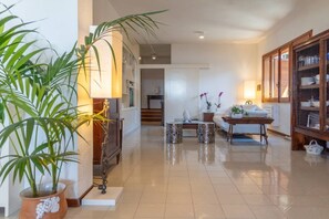 A spacious living area with a sofa, coffee table, and decorative plants.