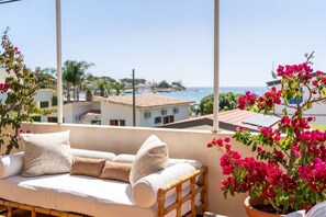 Ein Balkon mit einer Couch, Kissen und einem Blumentopf.