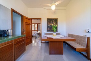 Una cocina con armarios de madera, una mesa de comedor con un banco y un ventilador de techo.