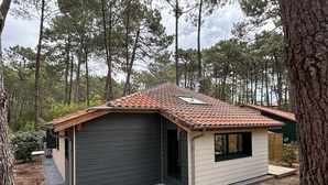 Une petite maison de plain-pied, avec un toit en pente, un garage et un petit porche.