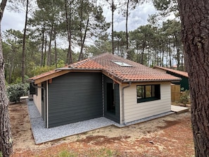 Een klein, gelijkvloers huis met een schuin dak, een garage en een klein terras.