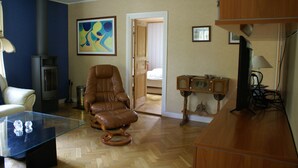 A living room with a leather armchair, a glass coffee table, a wooden cabinet, and a fireplace.