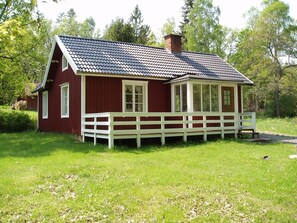 Une maison en bois rouge avec un porche blanc et une cheminée.