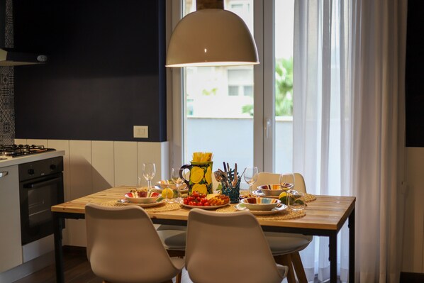 Une cuisine moderne avec une table à manger dressée pour quatre personnes, agrémentée d’un pichet de citrons, d’assiettes de nourriture et de verres à vin.
