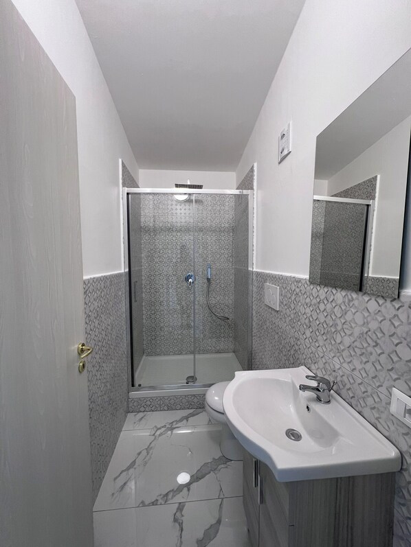 A bathroom with a shower, a sink, and a mirror.