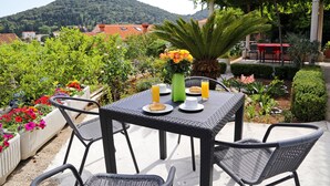 An outdoor dining area with a table set for two, surrounded by potted plants and flowers. - MODERN 1 BEDROOM APARTMENT - 100 mtrs from the beach, free parking, WIFI... (Dubrovnik)