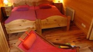 Une pièce de cabane en bois avec deux lits, un tapis rouge et une chaise en bois.