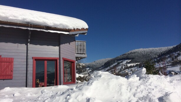 Un bâtiment avec une porte et des fenêtres rouges, entouré de neige.