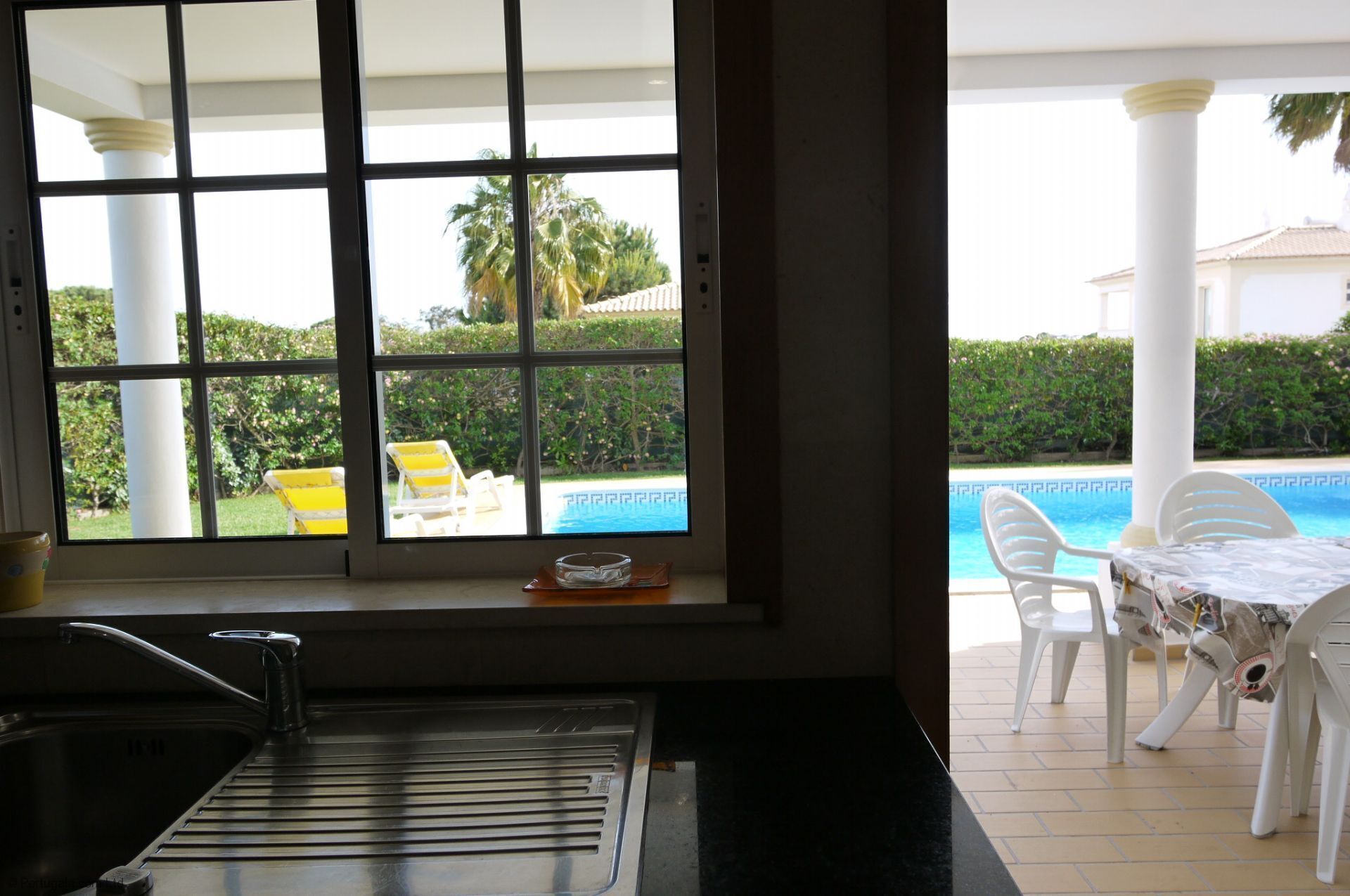 A kitchen with a window overlooking a pool area, including a table and chairs.
