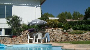 Una piscina con un muro de piedra y un edificio blanco al fondo.