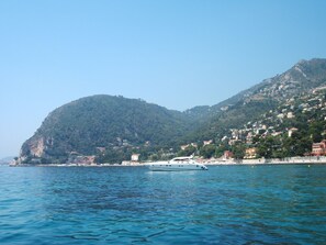 A coastal town with a boat docked near the shore, surrounded by hills and buildings.